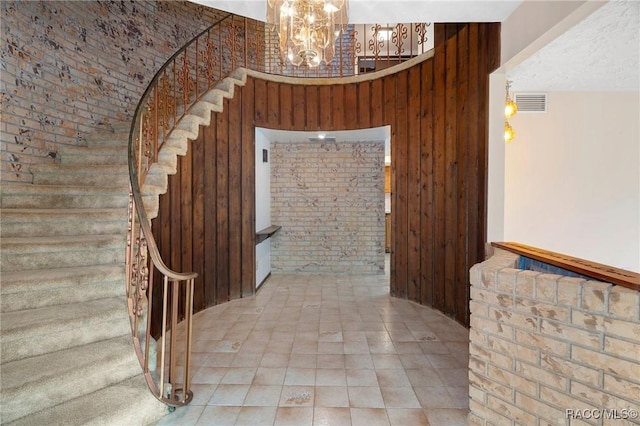 interior space with a chandelier, wooden walls, brick wall, and a high ceiling