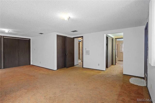 unfurnished bedroom with a textured ceiling, light carpet, and a closet