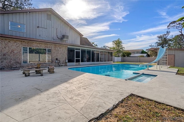 view of swimming pool featuring a patio area, a sunroom, a water slide, and an in ground hot tub