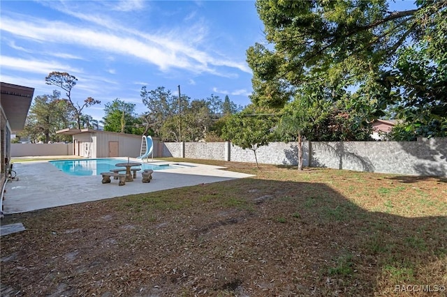 view of pool featuring a patio area, an outdoor structure, a yard, and a water slide