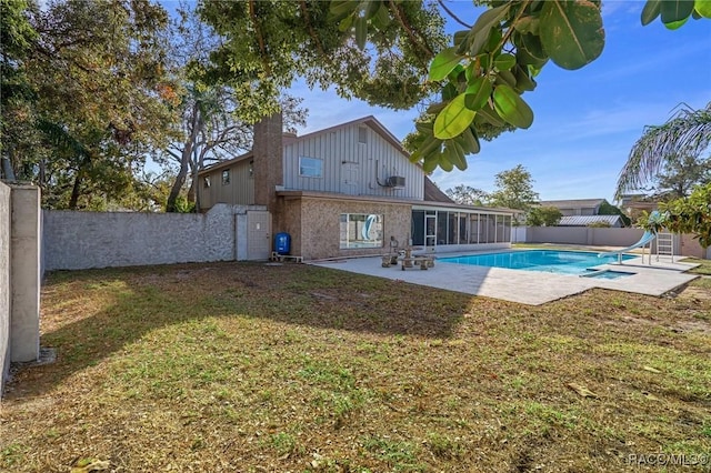 back of property with a fenced in pool, a patio area, and a lawn