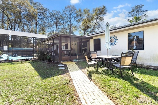 rear view of house featuring a yard, a pool, and stucco siding