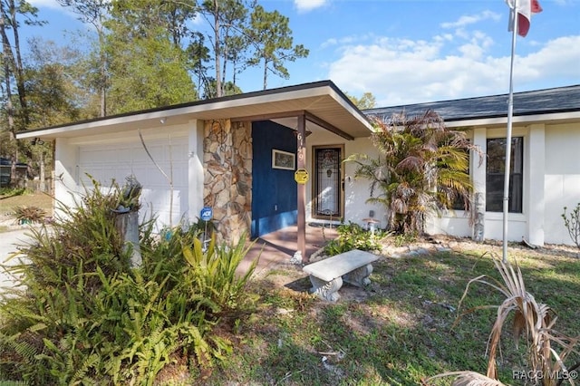 view of front of house with stucco siding, stone siding, and an attached garage