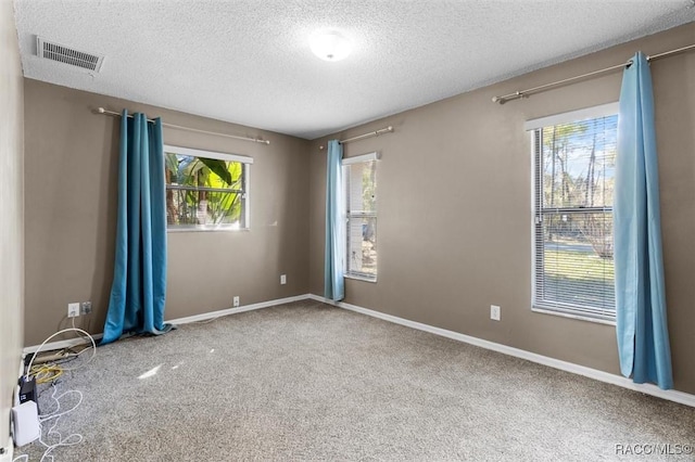 carpeted empty room with visible vents, baseboards, and a textured ceiling