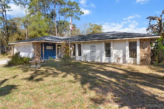 view of front of property featuring a front lawn, an attached garage, stone siding, and stucco siding