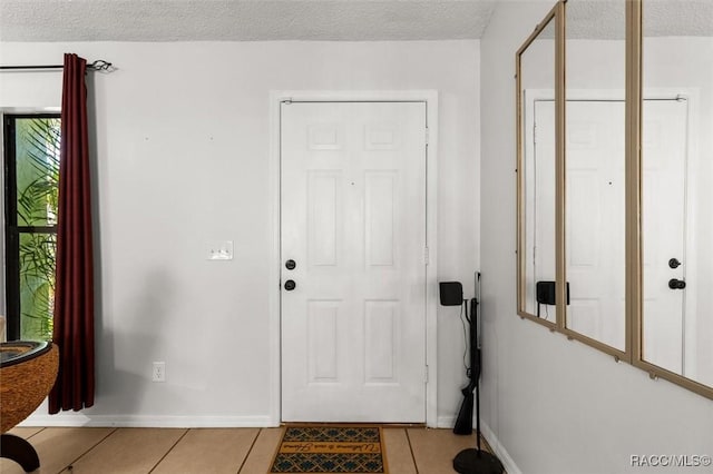 entryway featuring light tile patterned floors, baseboards, and a textured ceiling