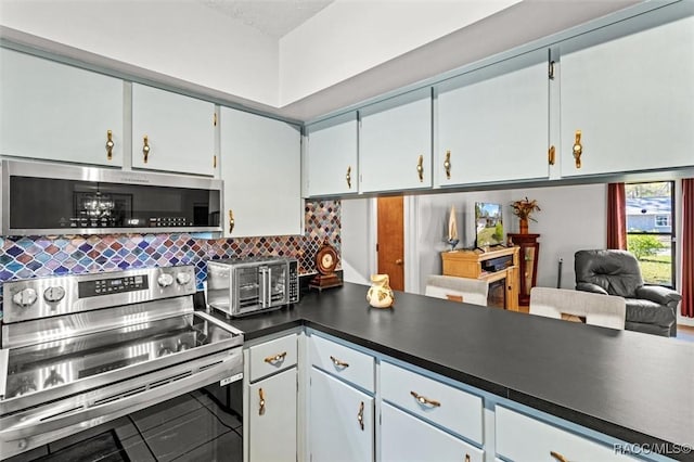 kitchen with tasteful backsplash, dark countertops, a toaster, appliances with stainless steel finishes, and white cabinets