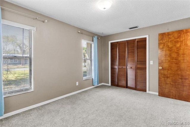 unfurnished bedroom with visible vents, baseboards, carpet floors, a closet, and a textured ceiling