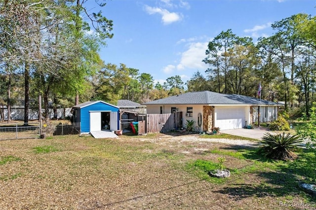 view of front of home featuring a shed, fence, a garage, and driveway