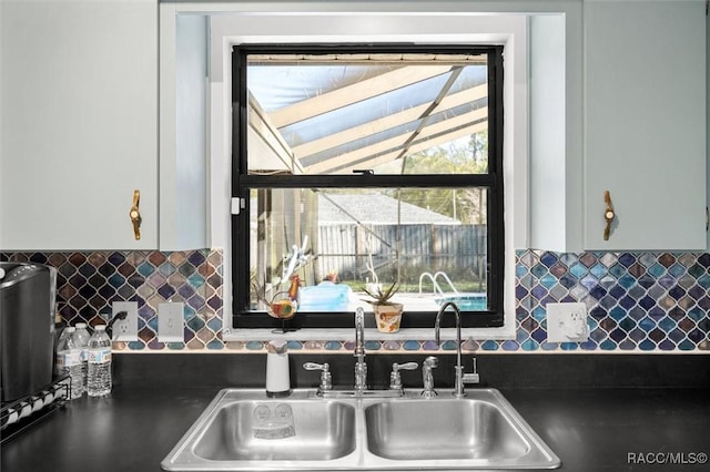 kitchen featuring a sink, backsplash, and dark countertops