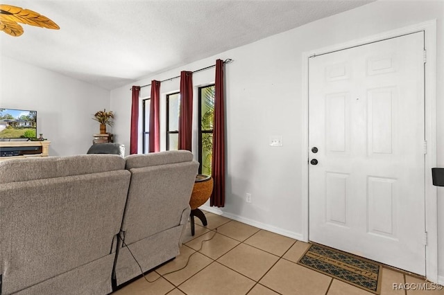 living room featuring light tile patterned flooring, a textured ceiling, and baseboards