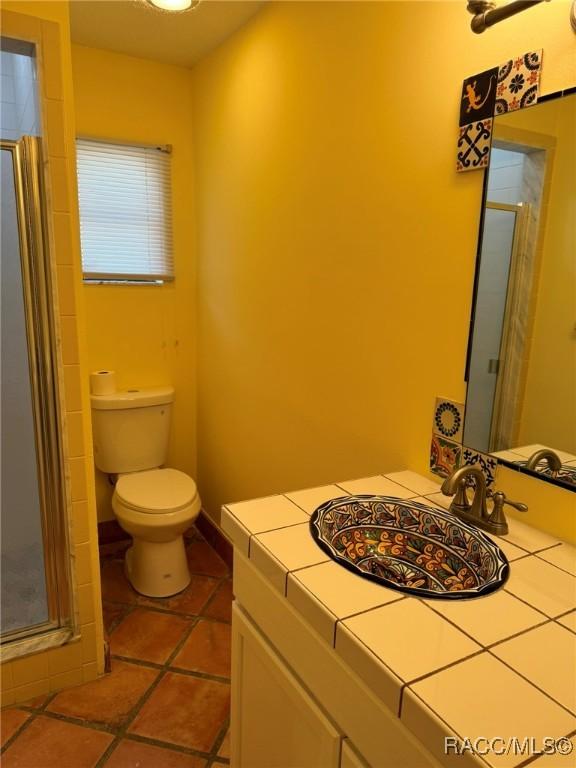 bathroom with tile patterned flooring, vanity, an enclosed shower, and toilet