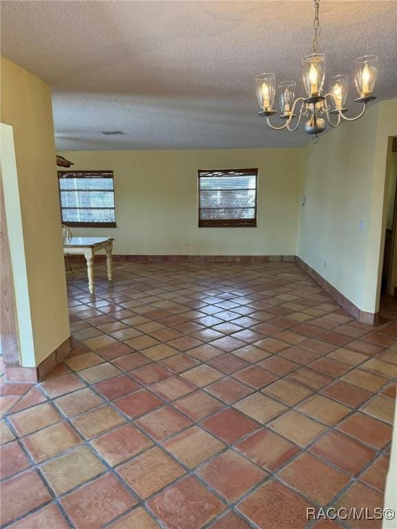 interior space featuring a wealth of natural light, dark tile patterned flooring, a textured ceiling, and a notable chandelier