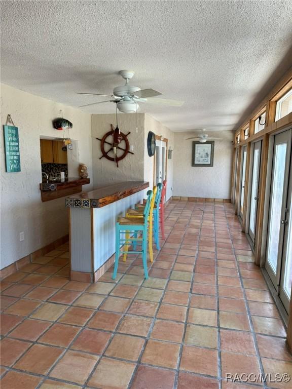 kitchen featuring plenty of natural light, ceiling fan, a kitchen bar, and kitchen peninsula