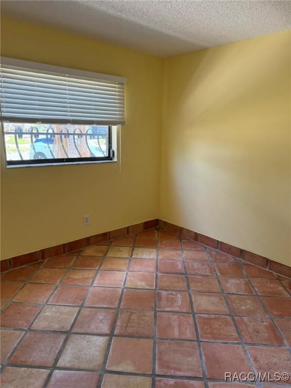 empty room featuring tile patterned flooring and a textured ceiling