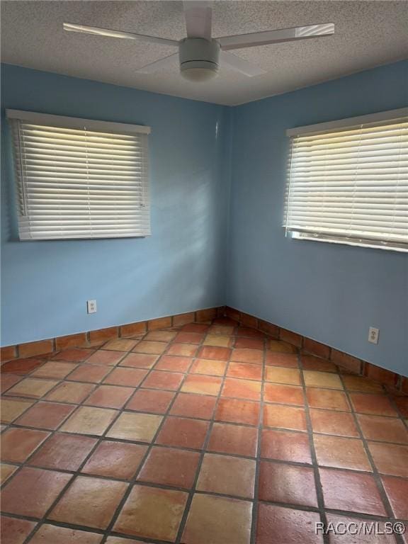 tiled empty room featuring a textured ceiling