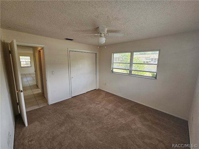 unfurnished bedroom featuring ceiling fan, carpet floors, a textured ceiling, and a closet