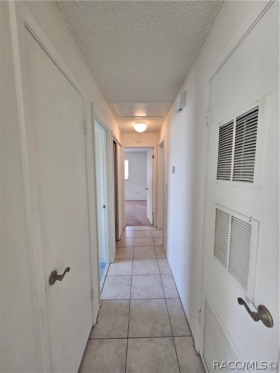 hallway with light tile patterned floors and a textured ceiling