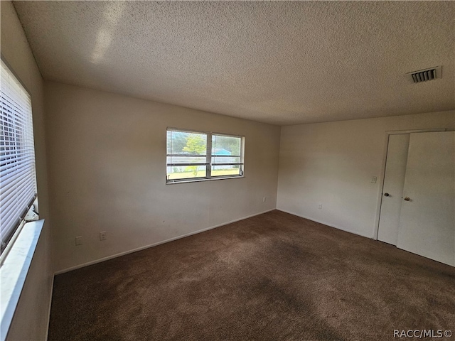 carpeted spare room with a textured ceiling