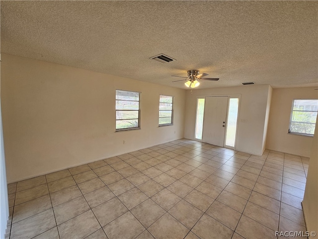 tiled spare room with ceiling fan and a textured ceiling