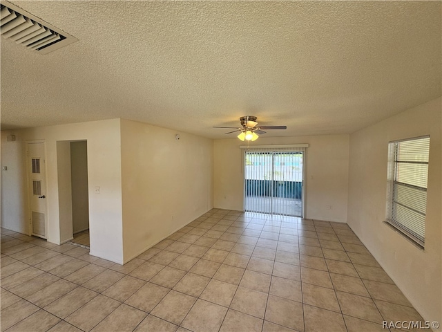 tiled spare room featuring a textured ceiling and ceiling fan