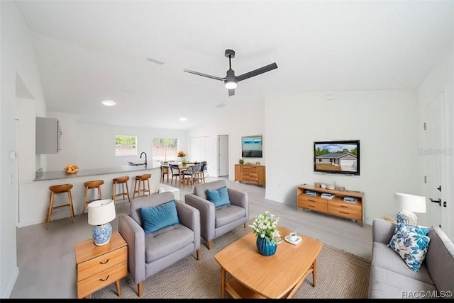living area with ceiling fan, light wood-style flooring, and lofted ceiling