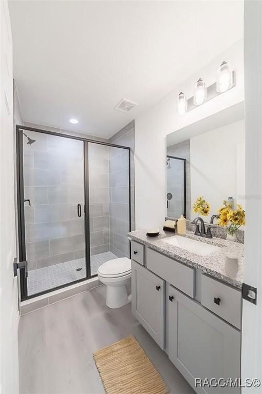 full bathroom with vanity, toilet, wood finished floors, and a shower stall