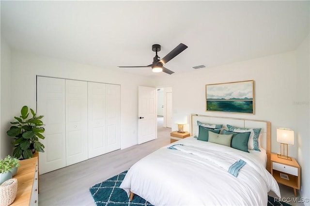 bedroom featuring a ceiling fan, a closet, visible vents, and wood finished floors