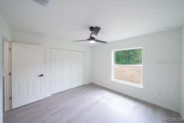 unfurnished bedroom featuring a closet, baseboards, visible vents, and wood finished floors