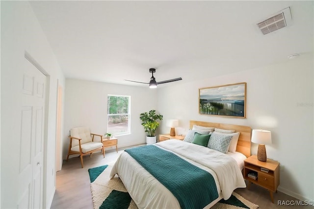 bedroom featuring a ceiling fan, baseboards, visible vents, and wood finished floors