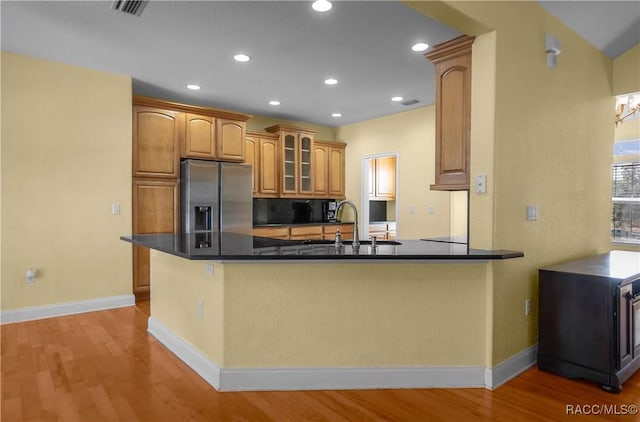 kitchen featuring sink, stainless steel fridge, light hardwood / wood-style floors, and kitchen peninsula