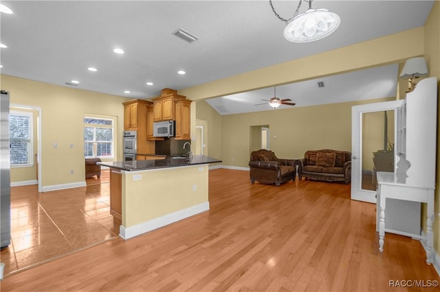 kitchen with lofted ceiling, stainless steel appliances, light hardwood / wood-style floors, and sink