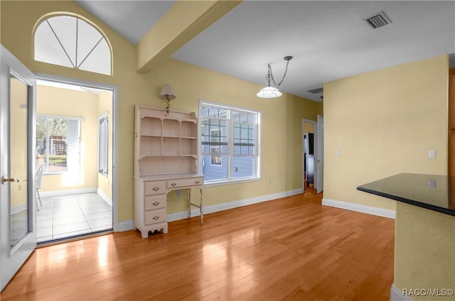 unfurnished dining area with lofted ceiling and light hardwood / wood-style floors