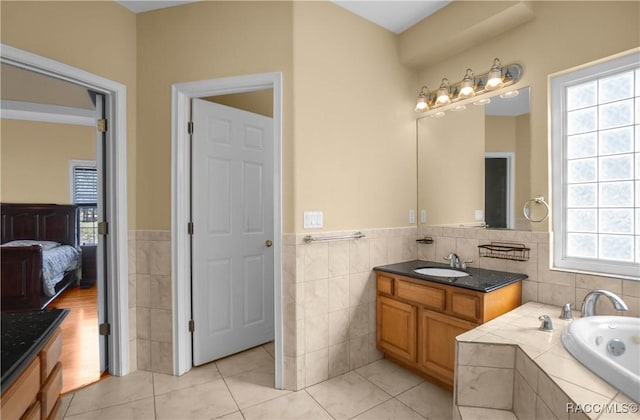 bathroom featuring vanity, tile patterned flooring, tiled bath, and tile walls