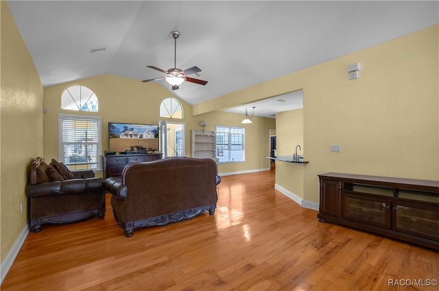 living room featuring vaulted ceiling, plenty of natural light, ceiling fan, and light wood-type flooring