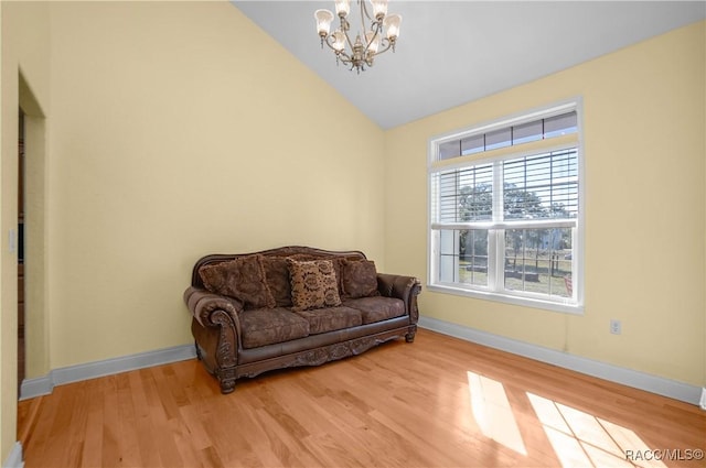 living area featuring a notable chandelier, light hardwood / wood-style flooring, and vaulted ceiling