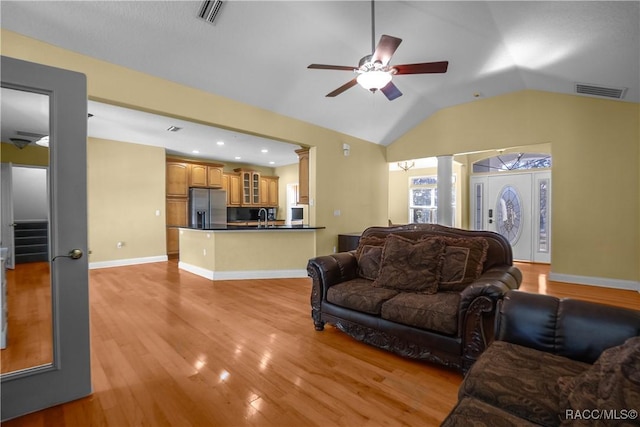 living room featuring ornate columns, lofted ceiling, sink, ceiling fan, and light wood-type flooring