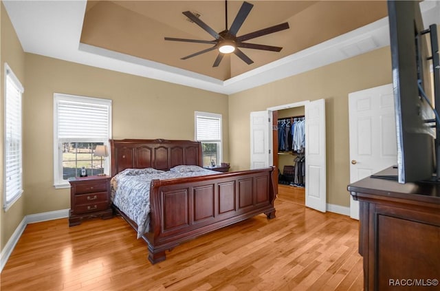 bedroom featuring a tray ceiling, light hardwood / wood-style floors, a closet, and a spacious closet