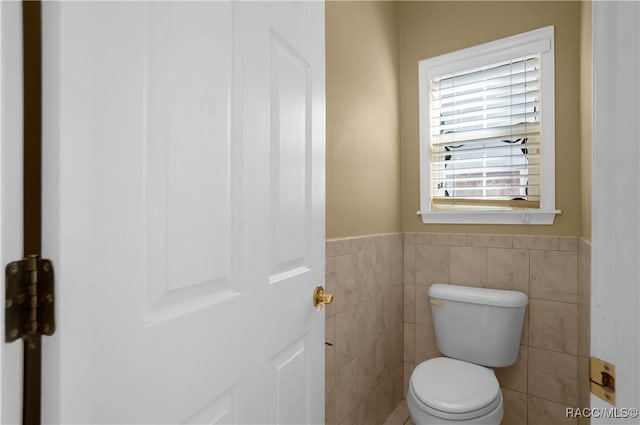 bathroom featuring tile walls and toilet