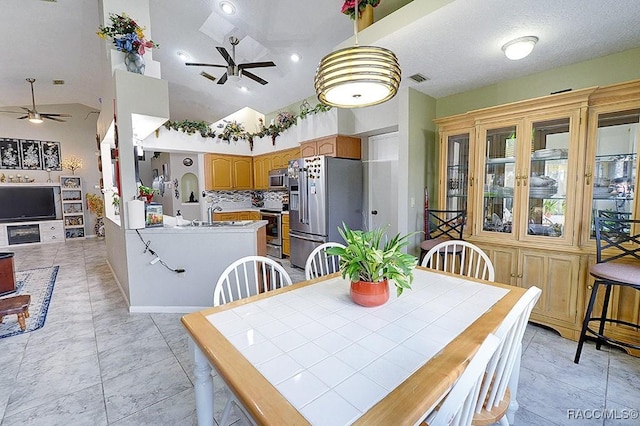 dining space with ceiling fan, high vaulted ceiling, and sink