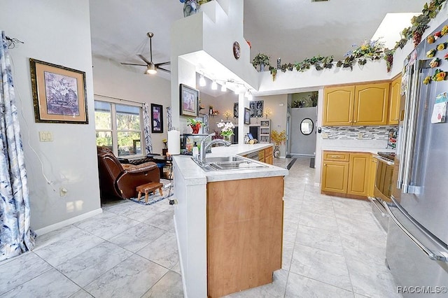 kitchen with kitchen peninsula, ceiling fan, sink, high end fridge, and backsplash