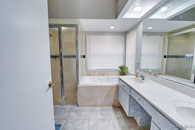 bathroom featuring shower with separate bathtub, vanity, tile patterned floors, and a skylight