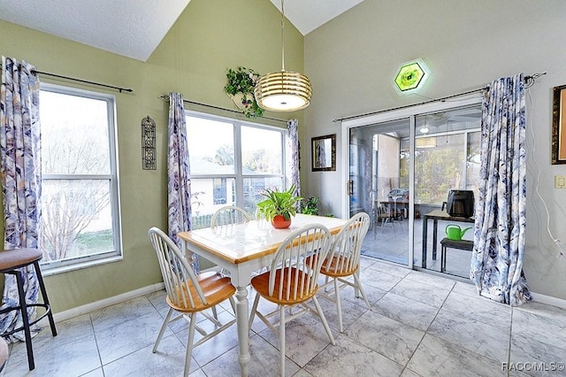 tiled dining space featuring high vaulted ceiling