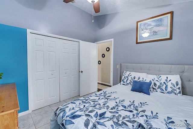 bedroom with a textured ceiling, a closet, light tile patterned floors, lofted ceiling, and ceiling fan