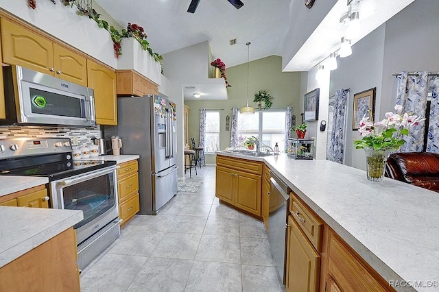 kitchen featuring vaulted ceiling, stainless steel appliances, sink, decorative light fixtures, and tasteful backsplash