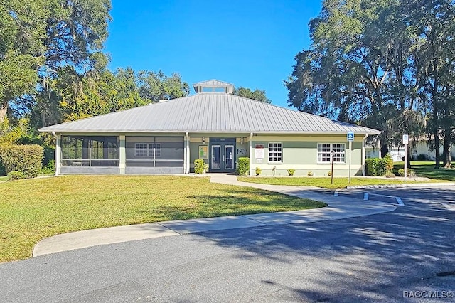 view of front of property featuring french doors, a front lawn, and a sunroom