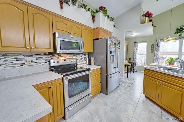 kitchen featuring vaulted ceiling, hanging light fixtures, stainless steel appliances, decorative backsplash, and sink