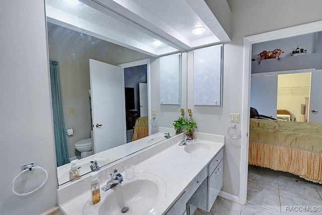 bathroom with a textured ceiling, vanity, and toilet