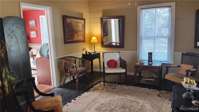 sitting room with dark wood-type flooring and wood walls