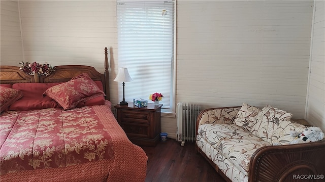 bedroom featuring wood walls, dark hardwood / wood-style flooring, and radiator heating unit